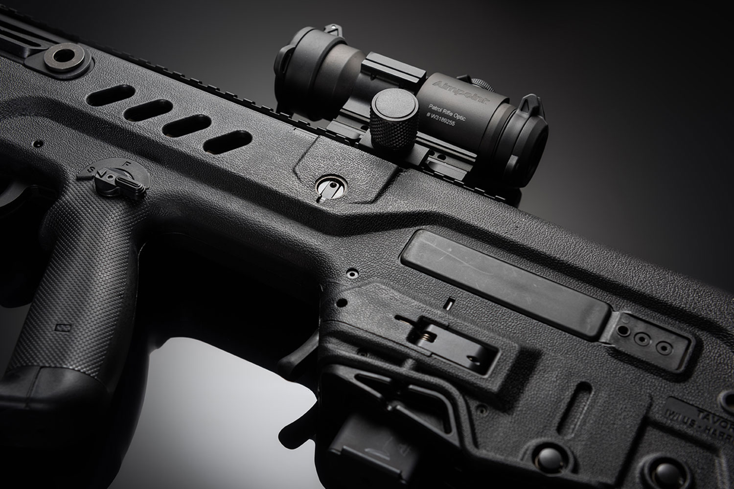Detail view of a rifle with a scope on a black background
